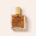 Lahvička tělového oleje NUXE Huile Prodigieuse Or 100 ml na béžovém pozadí – MrRizz